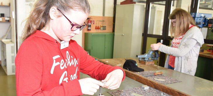 Konzentrierte Arbeit zweier Teilnehmerinnen bei Metallarbeiten mit dem Schneiden von Gewinden.